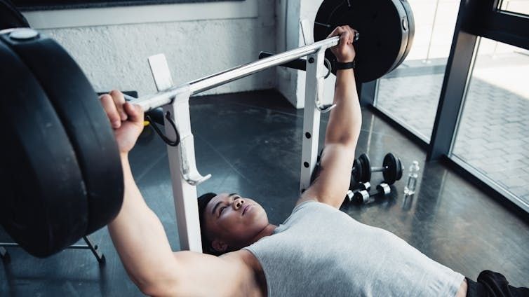Atleet voert een halterbankdruk uit in de sportschool