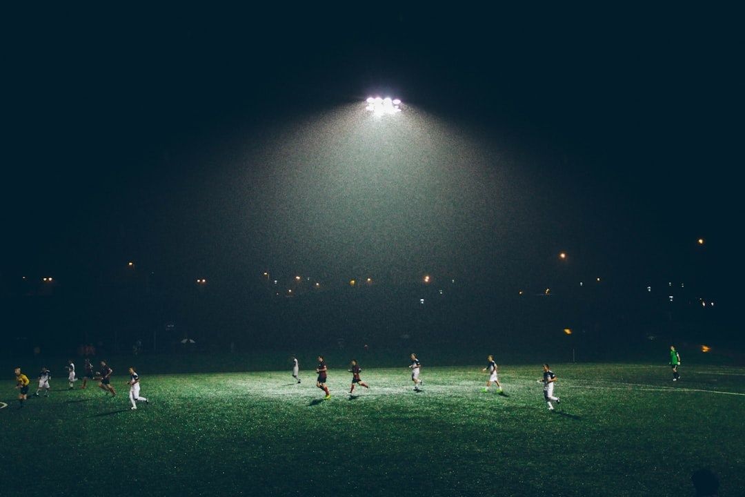 Voetballers spelen een wedstrijd onder felle stadionverlichting in het donker