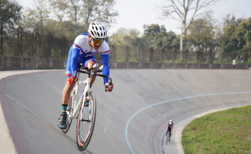 Baanwielrenner met helm rijdt schuin omhoog over een velodroombaan