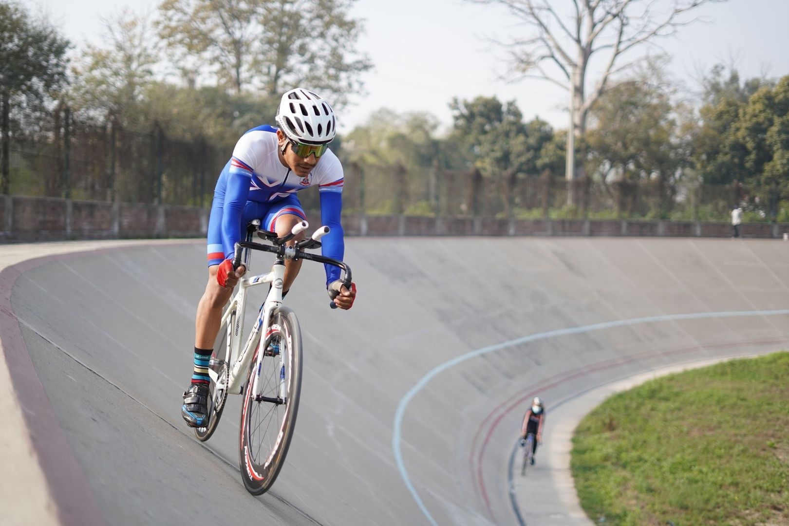 Baanwielrenner met helm rijdt schuin omhoog over een velodroombaan